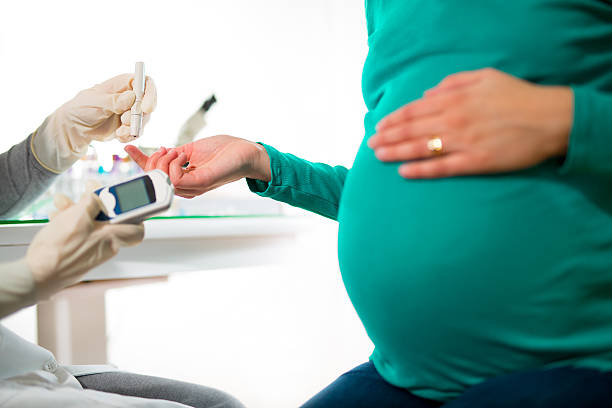 Pregnant Woman Having Blood Glucose Checked A close-up of a pregnant woman having her blood sugar/ glucose checked. gestational diabetes stock pictures, royalty-free photos & images