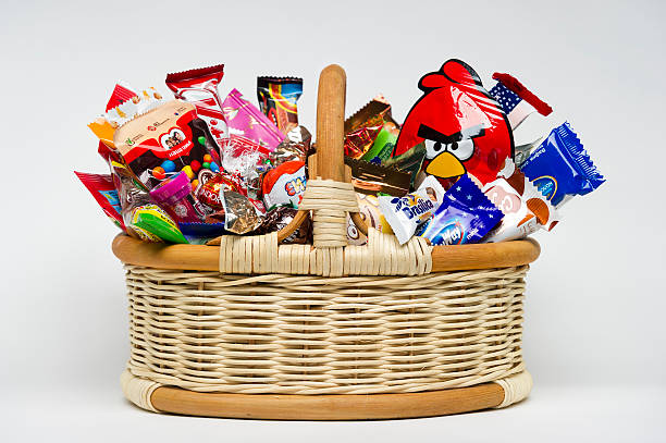 Candies in basket Moscow, Russia - January 02, 2016: Wicker basket with candies, chocolates and sweets for kids manufactured by different companies. Studio shot. Isolated on white. eye candy stock pictures, royalty-free photos & images