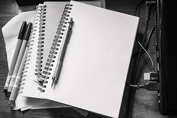 Opened notebook with pencil, marker pen and laptop on working table, black and white, monochrome