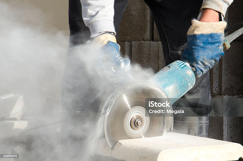 Grinder, Electric saw, Dust, Cut, Protective gloves, Blade Worker cutting stone with grinder. Dust Stock Photo