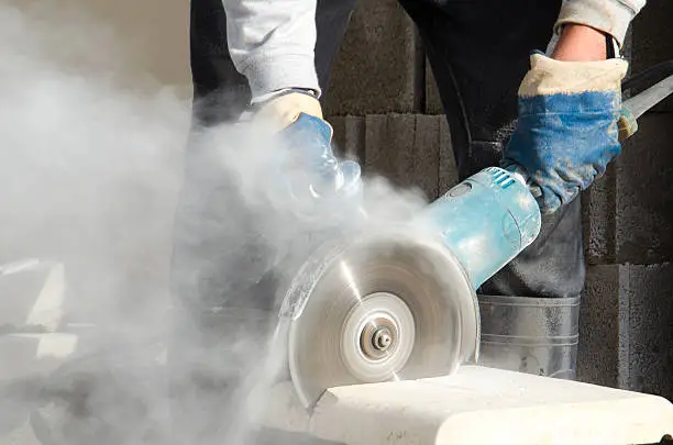 Worker cutting stone with grinder.