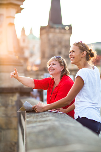 Mother and daughter traveling - two female tourists studying a map, discovering a new city