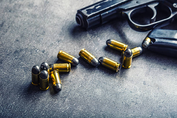 istock 9mm pistol gun and bullets strewn on the table 512974222