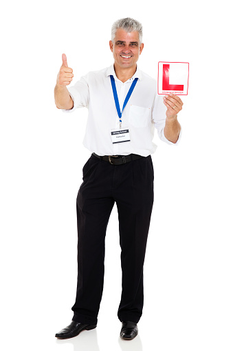 portrait of professional senior driving instructor holding L sign