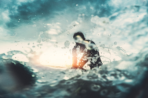 Portrait of a determined surfer who is riding his surfboard on a wave during a stormy weather