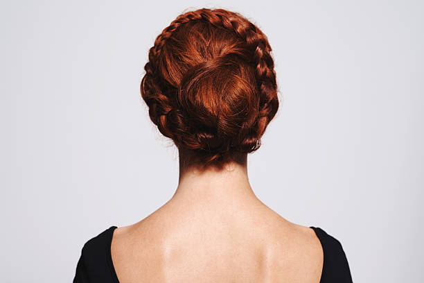 Braids and buns Studio shot of a redhead woman with a braided up-do posing against a gray background braided buns stock pictures, royalty-free photos & images