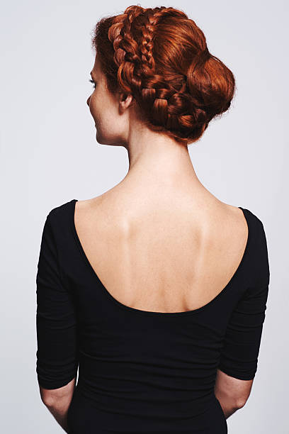Buns don't have to be boring Studio shot of a redhead woman with a braided up-do posing against a gray background braided buns stock pictures, royalty-free photos & images