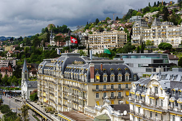 Architecture of a famous and luxury hotel in Montreux, Switzerland Montreux, Switzerland - May 19, 2013: Aerial view of front facade of famous a five star luxury hotel "Fairmont Le Montreux Palace". Hotel was built in 1906 and is located at High Street (Grand Rue) in Montreux. Above the hotel on the hillside there are visible many other city buildings montreux stock pictures, royalty-free photos & images