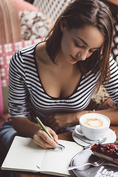 istock Girl drawing a cup of coffee in the notebook 512980985