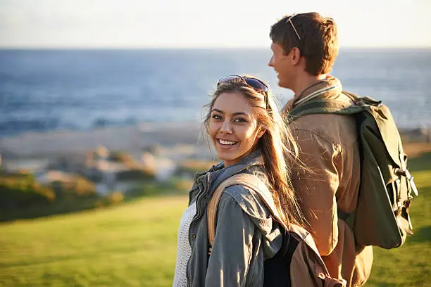 Portrait of a young couple standing on the edge of an embankment overlooking the ocean