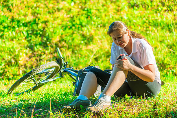 istock cyclist holds  his bruised knee while sitting on the lawn 512982695