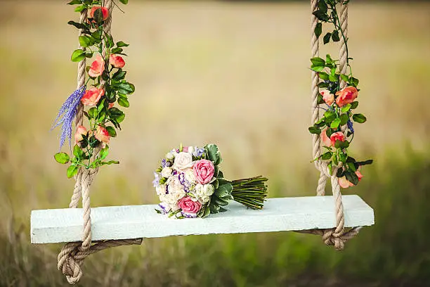 Photo of Wedding bouquet of peonies lying on white bench swing decorated