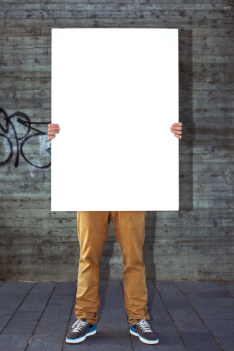 man standing in urban scene with blank poster in his hands