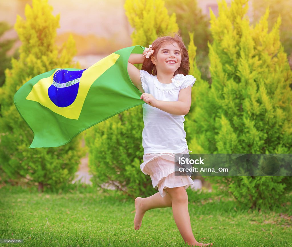 Happy little football fan Happy little football fan, cute little girl running on the park with national Brazil flag waving on the wind, sportive childhood, football championship concept Brazil Stock Photo