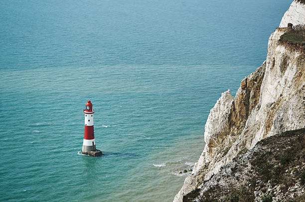 istock Red and white lighthouse in the sea with rock 512987088