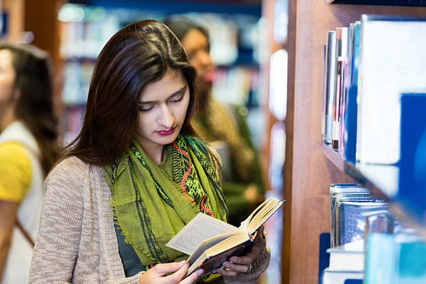 istock Trendy college girl reading book in library 512989026