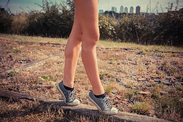 A young woman is walking on her tip toes on a wooden beam on the ground