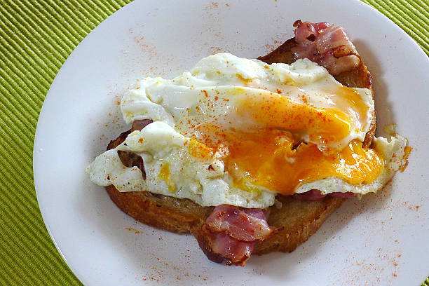 Fried egg with ham and peppers on bread stock photo