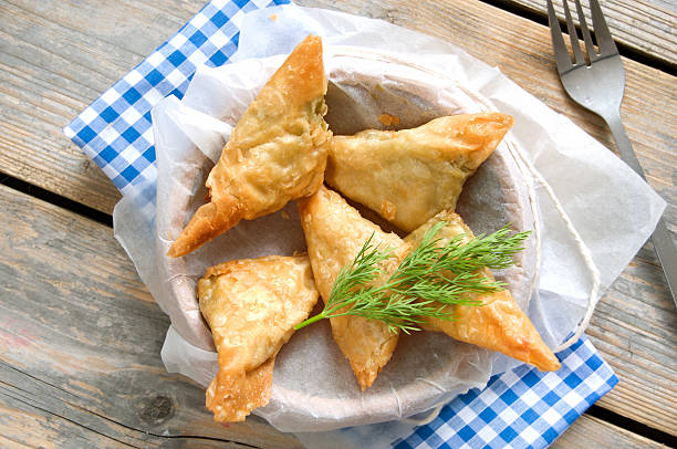 Greek feta and spinach filo pastry triangles Greek cheese stuffed filo pastry with herbs in a dish on a wooden background filo pastry stock pictures, royalty-free photos & images