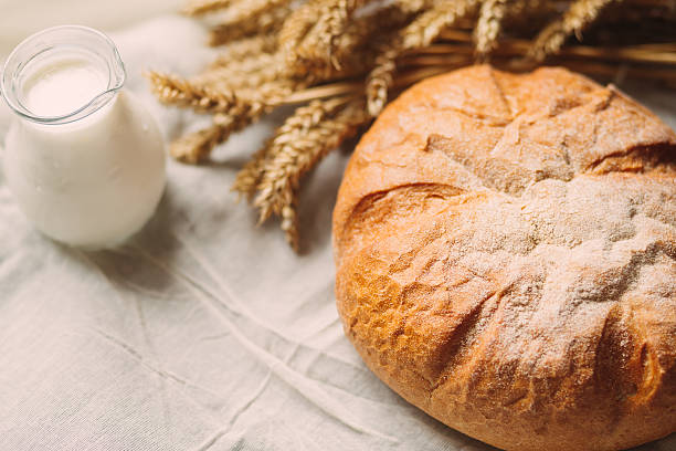 istock Glass jug with milk and bread on white textile 512993974