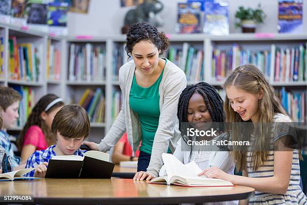 Elementary Students Working With Teacher In Library Stock Photo - Download Image Now