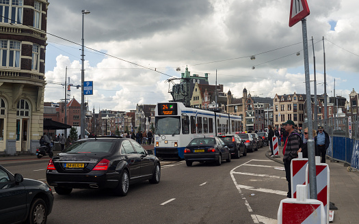 Amsterdam, The Netherlands - September 26, 2015: City life in Amsterdam. Old traditional architecture, road car traffic, public transport and walking people. 