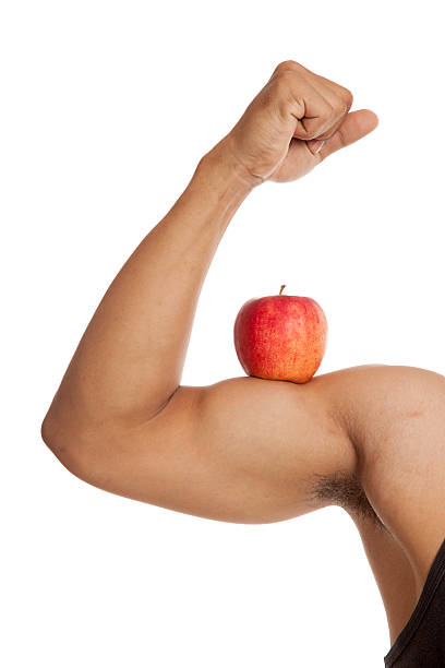 istock Muscular Asian man's arm  flexing biceps with red apple 512995728