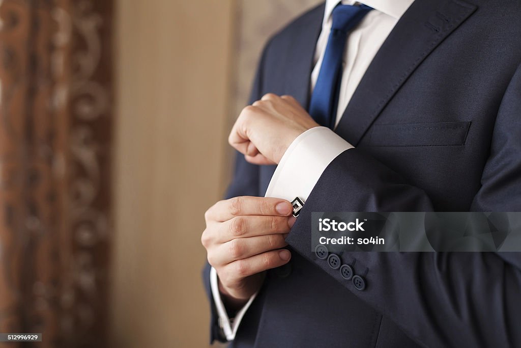 Closeup of a man in black suit correcting a sleeve Closeup of a man in black suit correcting a sleeve. Adjusting Stock Photo