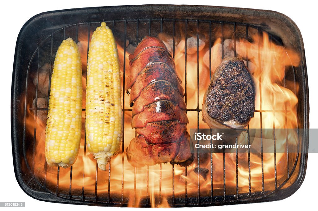 Surf and Turf Downward looking shot of filet mignon, lobster tail and corn on the cob cooking on a charcoal barbecue, isolated on white Lobster - Seafood Stock Photo
