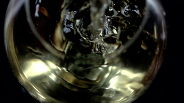White wine being poured into a wineglass, bubble, bottom view, black, closeup, slowmotion