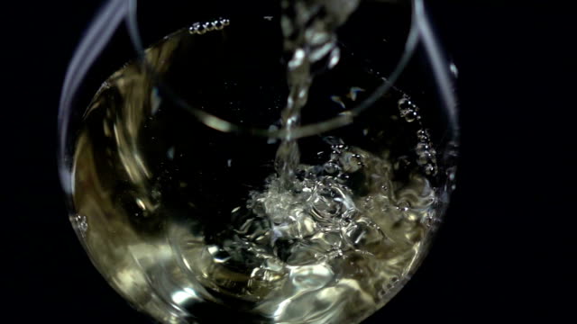 White wine being poured into a wineglass, bubble, view from above, black, closeup, slowmotion