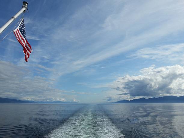 istock Boat wake and American Flag among open water 513040982