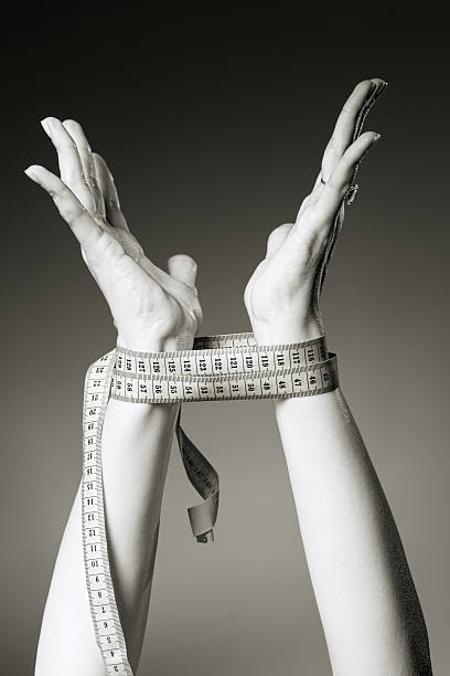 Opened female hands, tied up with measuring tape. Diet slave concept
