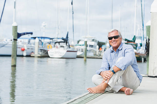 istock Senior man at marina, sitting on boat dock 513045974