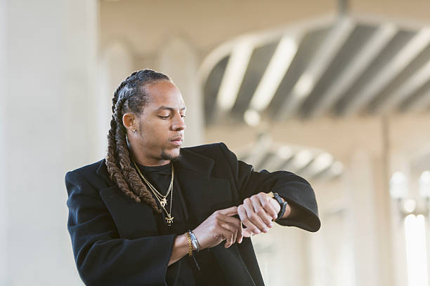 Young mixed race man in black coat looking at watch