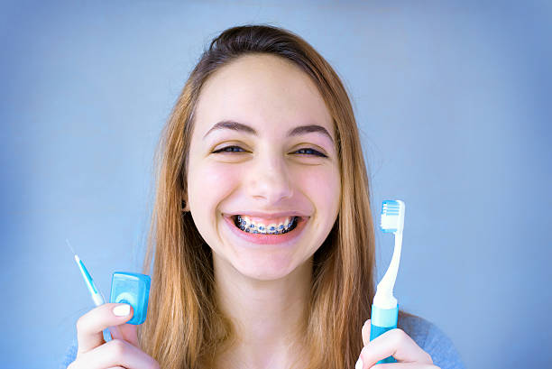 Beautiful smiling girl with retainer for teeth brushing teeth . stock photo