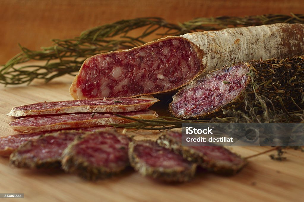 Dried french sausages Sliced dried french sausages with rosemary on wooden table Chopped Food Stock Photo