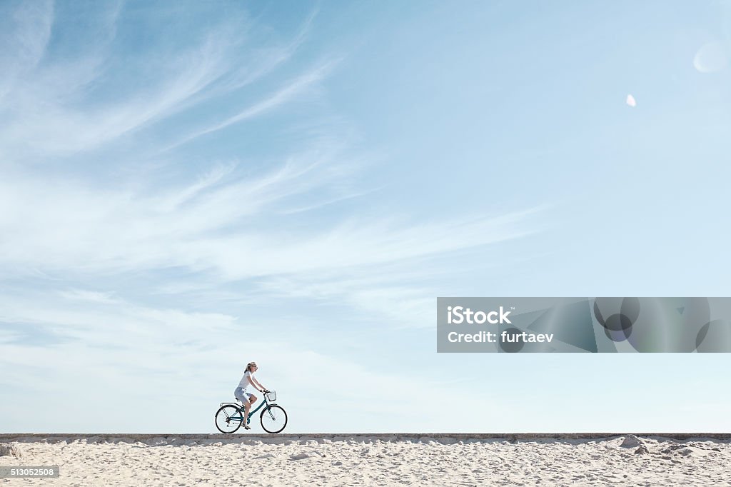 Girl enjoying bike ride under sky Young woman riding bicycle with basket against blue sky during summer - healthy lifestyle concept Cycling Stock Photo