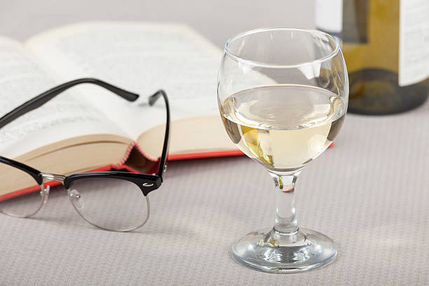 istock Glass of wine on a table with a open book 513053760