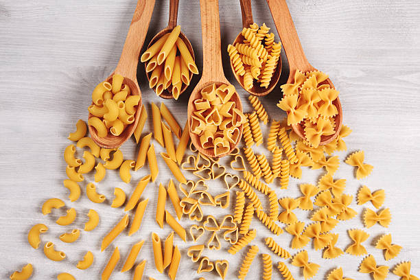 istock Different types of pasta lying in wooden spoons 513053906