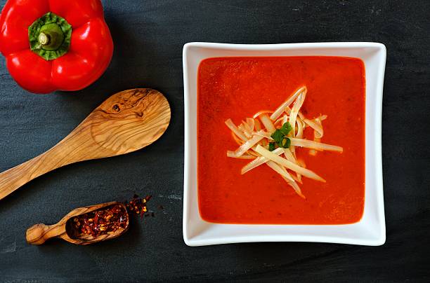 istock Red pepper soup overhead scene on slate background 513054054
