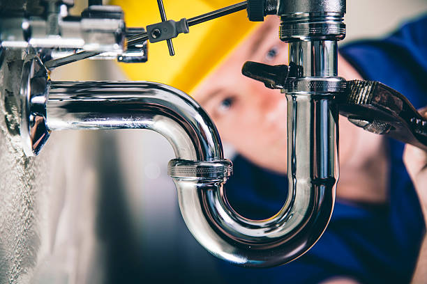 Now it should be ok! Plumber fixing a drain with adjustable wrench. Focus on drain, plumber defocused in back. pipe tube photos stock pictures, royalty-free photos & images
