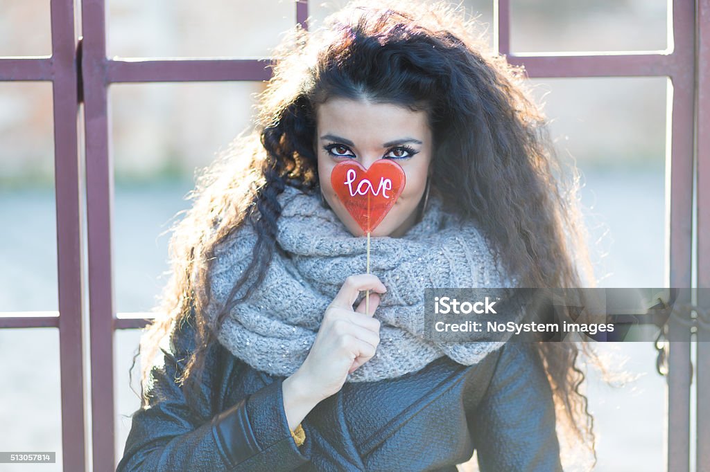 Girl with love lollipop Beautiful girl hiding her face behind big red, heart shaped lollipop with love word on it Heart Shape Stock Photo