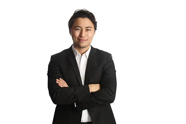 An attractive businessman wearing a black blazer with a white shirt, standing against a white background looking at camera. Smile on his face. 