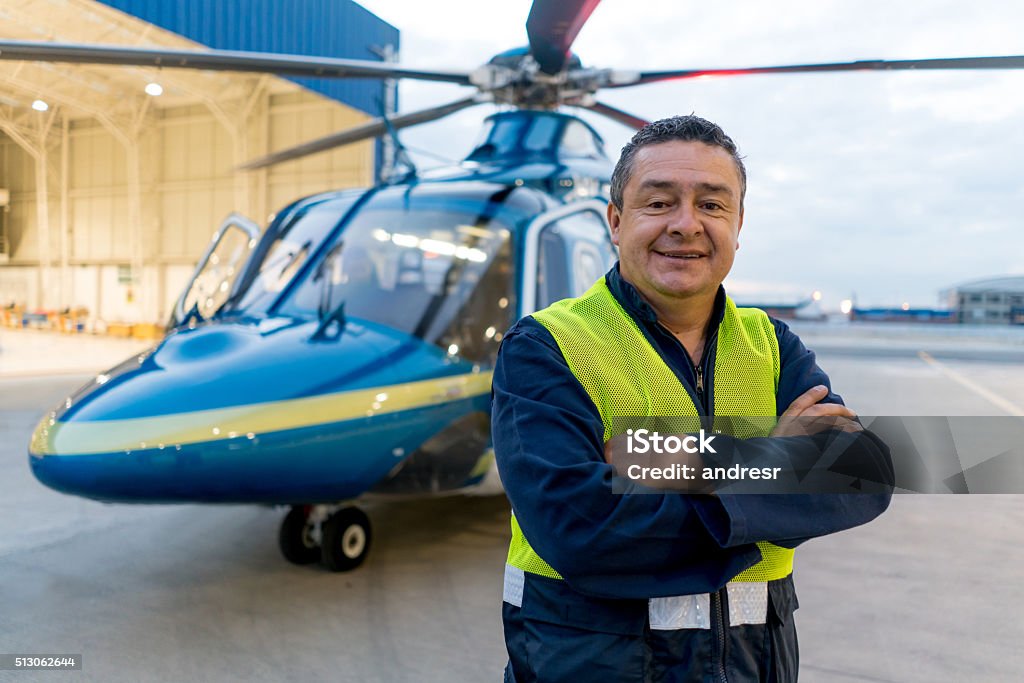 Man working at a helicopter hangar Man working at a helicopter hangar and looking at the camera smiling Helicopter Pilot Stock Photo