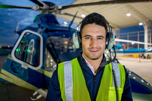 Handsome male pilot flying a helicopter and wearing headset