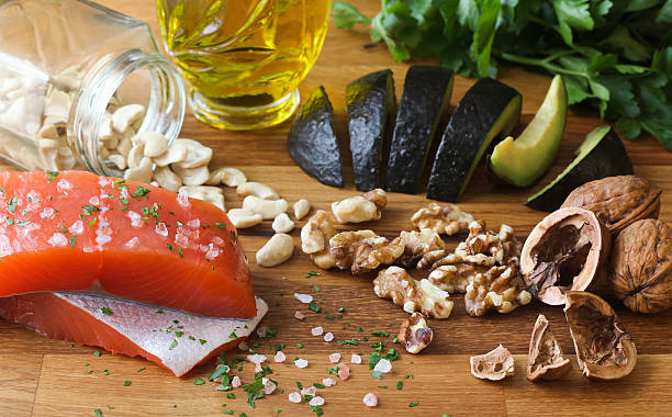 Omega-3 Foods on Wood Background Salmon seasoned with salt, cashews, walnuts, sliced avocado, and olive oil on a butcher block, garnished with parsley. mediterranean food stock pictures, royalty-free photos & images