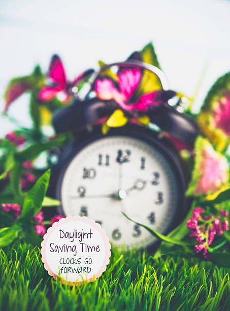 Clock in grass with spring foliage. Daylight Savings Time reminder