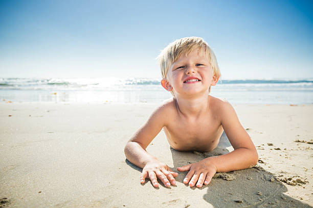 istock Blonde Three Year Old Boy Lying On The Beach 513065236