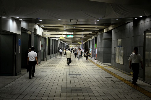 Tokyo, Japan - September 19, 2013: Office workers and pedestrians walk through an underground walkway passage leading to Shinjuku train station in Tokyo Japan. Various signs are seen inside the tunnel. 